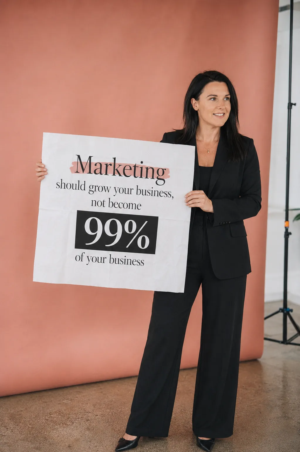 Katie holding a sign reading: Marketing should grow your business, not become 99% of your business