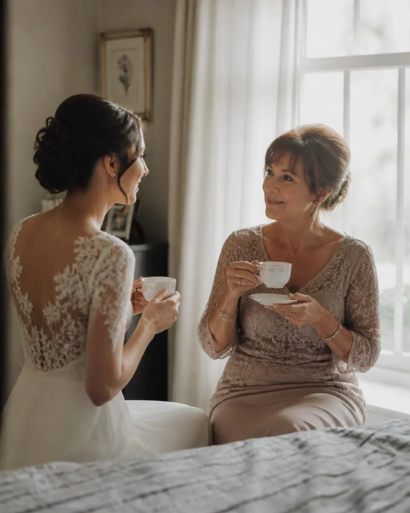 Bride and her mother sharing a quiet cup of tea in soft morning light