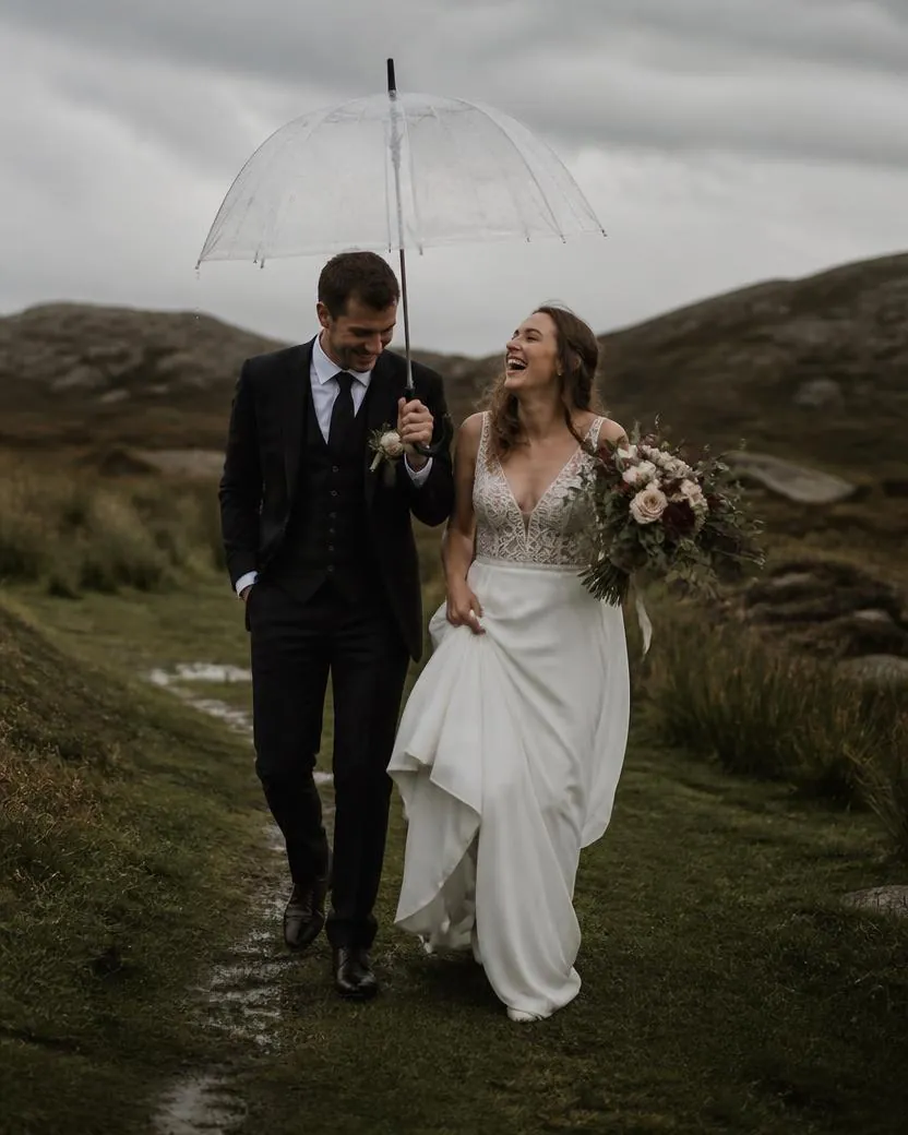 Couple laughing under a clear umbrella walking between rain showers